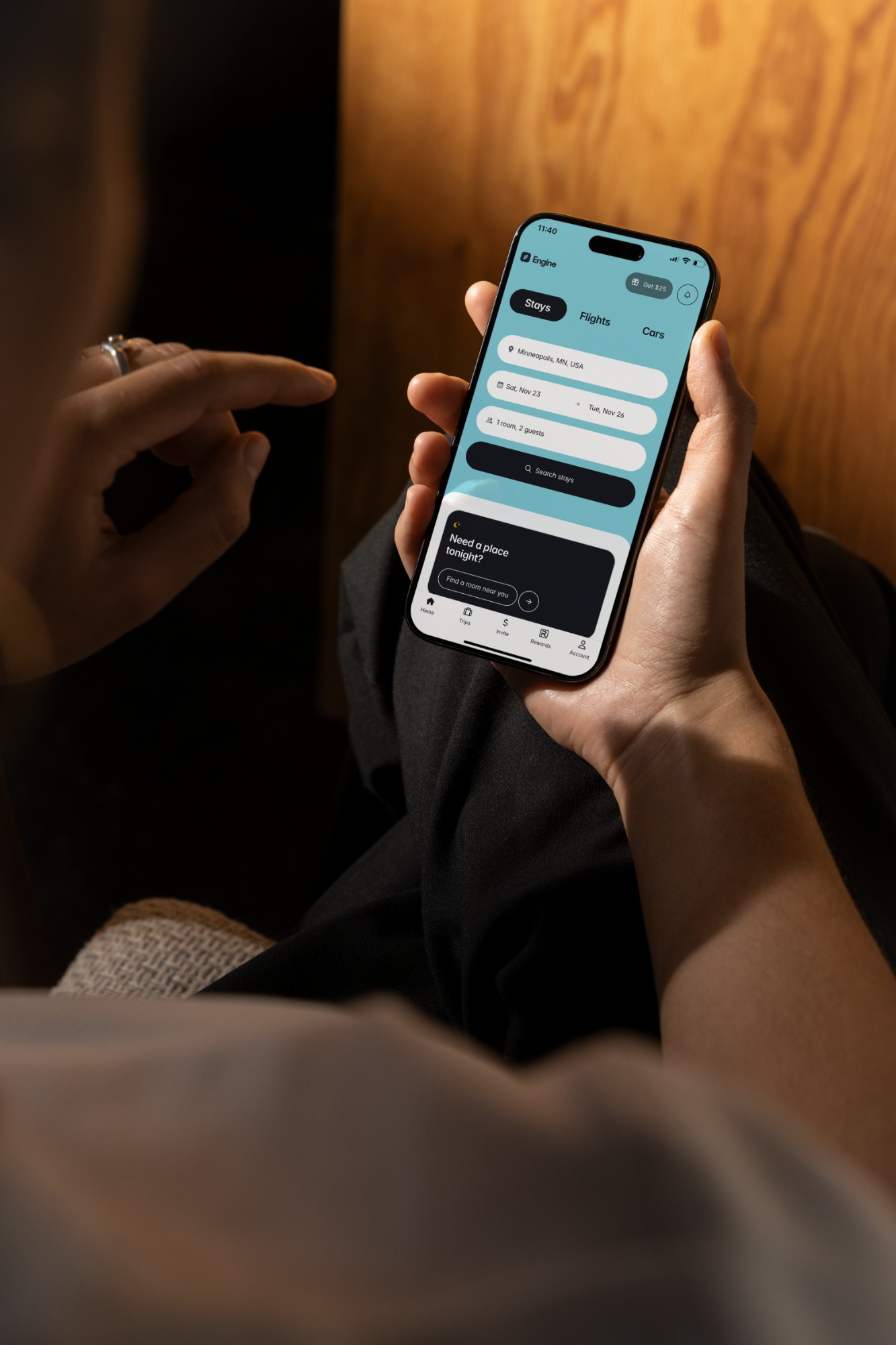 Hands holding a phone with Engine's mobile app open to the lodging search screen