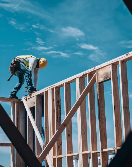 A construction worker walking on a house frame